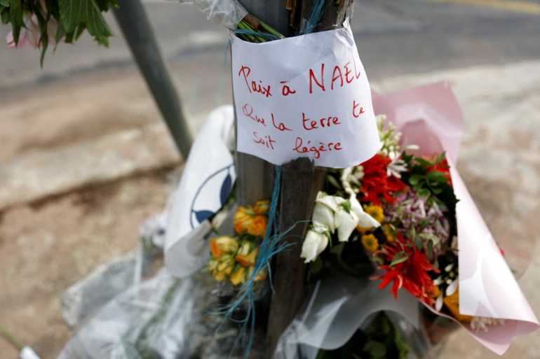Bunga terlihat di lokasi di mana Nahel dibunuh oleh seorang petugas polisi Prancis saat berhenti lalu lintas.  Pesan itu berbunyi 'Damai untuk Nael, semoga bumi menjadi cahayamu'