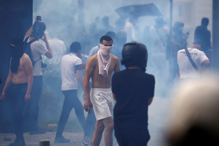 Masked protesters walk amid tear gas during clashes at a march in tribute to Nahel, a 17-year-old teenager killed by a French police officer during a traffic stop, in Nanterre, Paris suburb, France, June 29, 2023. REUTERS/Sarah Meyssonnier