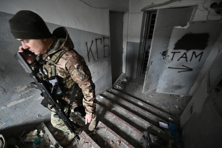 A Ukrainian policeman walks in a basement of the regional police headquarters, allegedly used as a torture site of pro-Ukrainian citizens during the Russian occupation, in Kherson on January 31, 2023. - After invading Russian forces retreated from southern Ukrainian city of Kherson, police have discovered detention facilities allegedly used to torture captured Ukrainians. All what was left is floors filled with trashed personal belongings, lonely chair in a dark basement room, and Russian anthem written on the walls. (Photo by Genya SAVILOV / AFP)