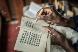 A member of the Hamere Berhan Institute writes scriptures in the Ge&#39;ez language on parchment made of goat skin. [Amanuel Sileshi/AFP]