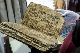 the Chaldean Catholic Archbishop of Mosul Michaeel Najeeb holds an old damaged Syriac-language Christian codex at the Eastern Manuscript Digitisation Centre (CNMO) in Arbil, the capital of Iraq's autonomous northern Kurdish region.