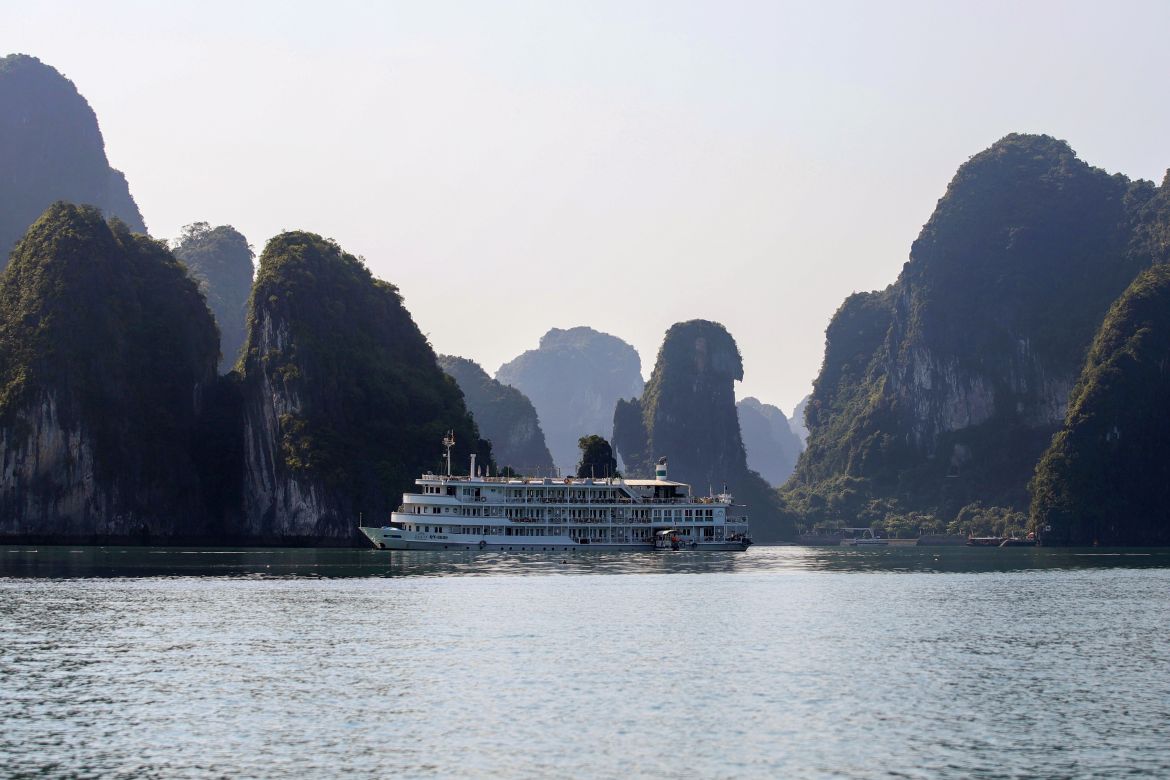 a tourist boat next to karst formations in Ha Long Bay