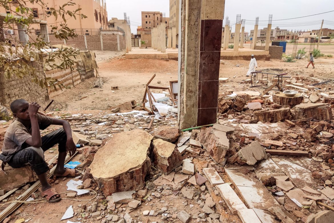 A youth sits by the rubble of a house that was hit by an artillery shell in the Azhari district in the south of Khartoum