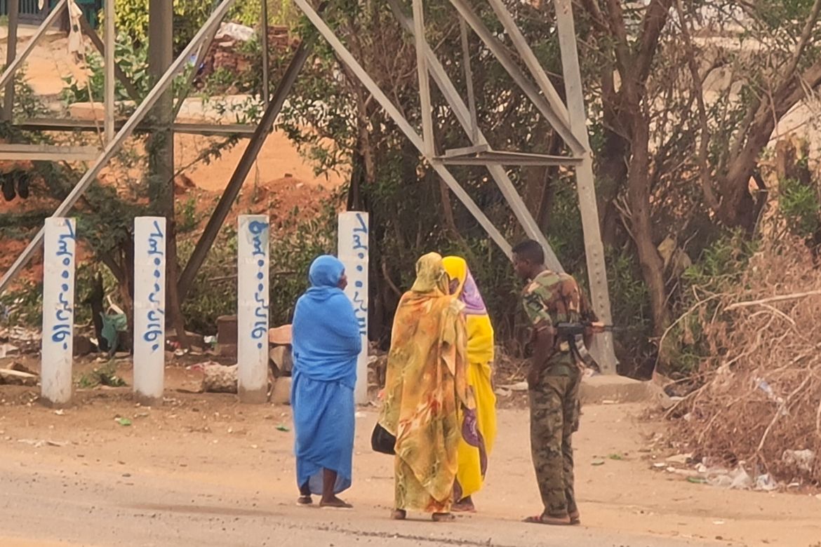 An army soldier talks to women on a street in Khartoum on June 6,