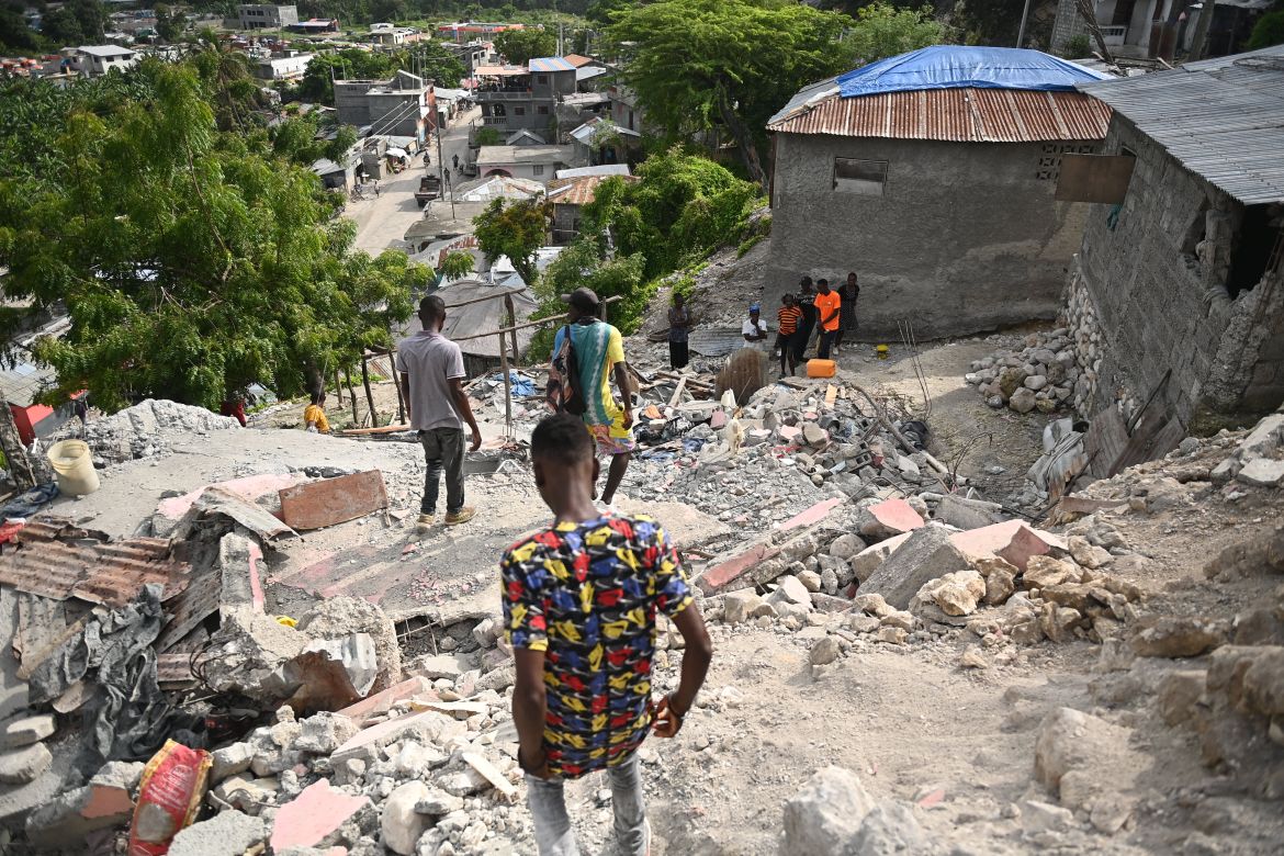 People walk amongst damaged buildings in Jeremie, Haiti