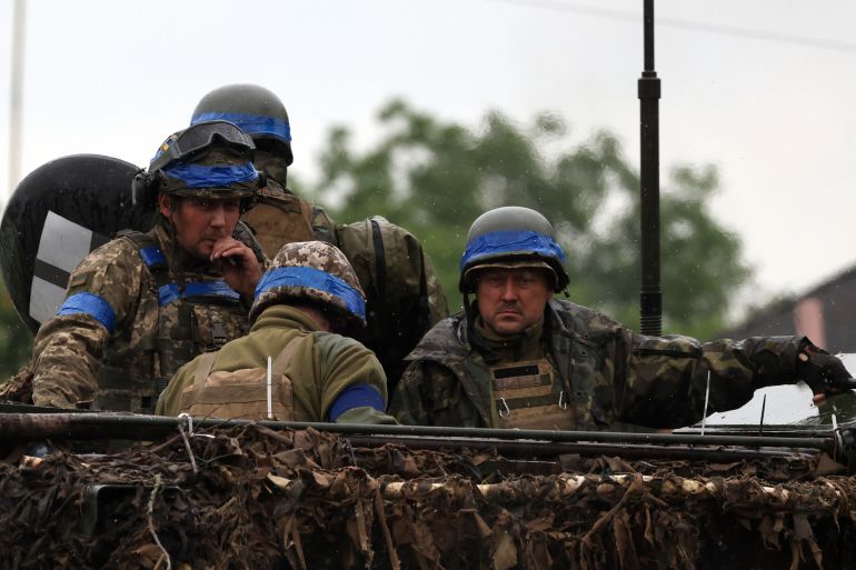 Ukrainian solders on top of an armoured vehicle. They are in battle dress with helmets