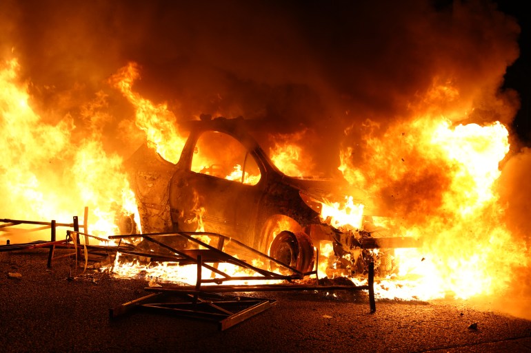 A vehicle burns, destroyed by protesters in Nanterre, west of Paris