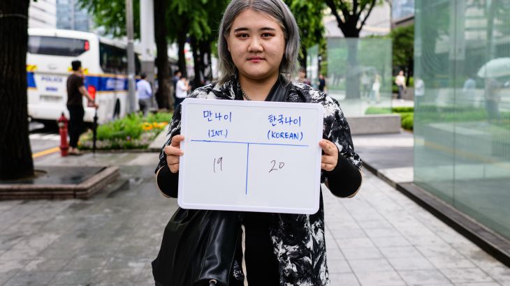 Kim Hye-rim, a university student studying computer science, poses with a whiteboard showing her international age, 19, and Korean age, 20