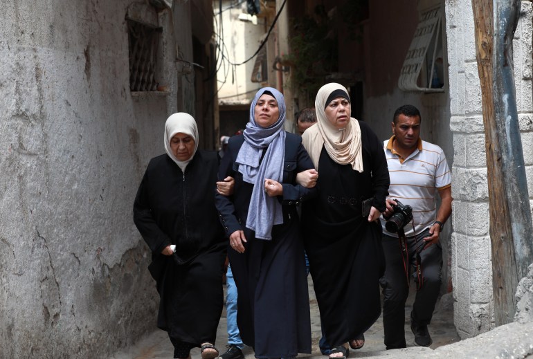 Three female mourners walking down an alley