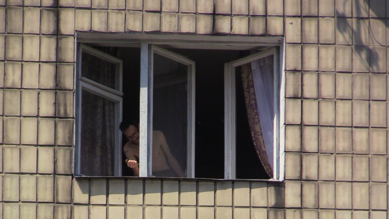 Seorang penduduk Kyiv Timur mengeluarkan pecahan kaca dari jendelanya setelah rudal jelajah Rusia ditembak jatuh Rabu pagi-1685630704