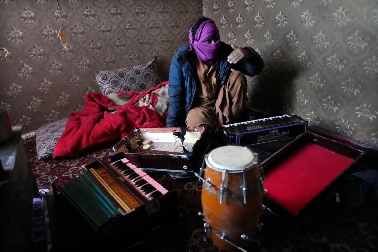 Zabiullah Nuri, 45, covers his face to protect his identity, as he shows his musical instruments during an interview with The Associated Press, in Kabul