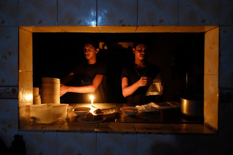 Staff at an eatery work by candle light after a failure in Bangladesh's national power grid plunged much of the country into a blackout in Dhaka, Bangladesh, Tuesday, Oct.4, 2022. (AP Photo/Mahmud Hossain Opu)