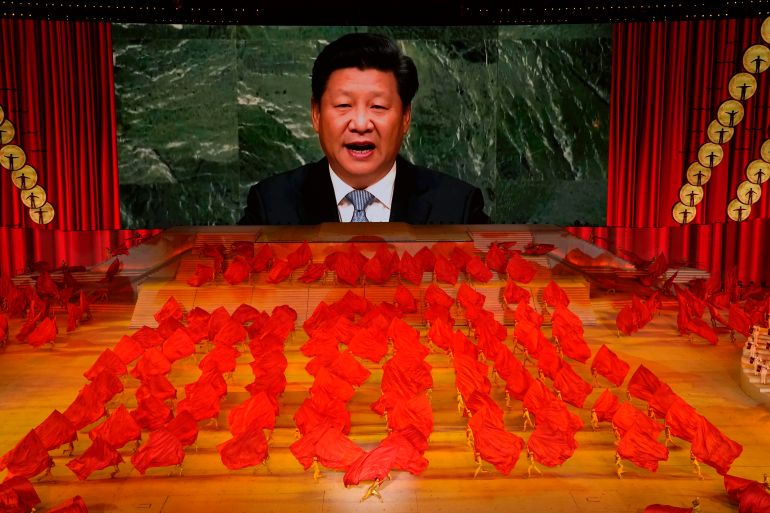 Xi Jinping on a giant screen as performers dance with red flags