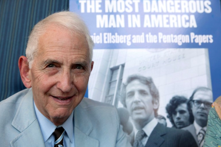 Ellsberg in front of a poster