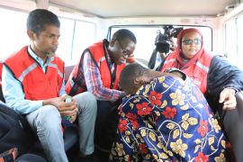 A woman, one of the followers of a cult that has killed dozens bends as she sits next to Kenya Red Cross officials inside a car after being rescued by police in a forest in Shakahola, outskirts of Malindi town, Kenyan Coast