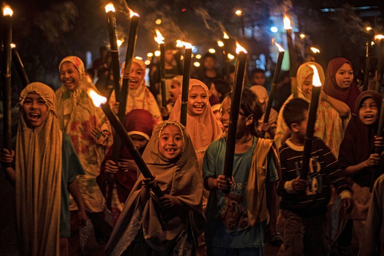 Gadis-gadis Muslim membawa obor saat mereka berparade untuk merayakan Idul Fitri di Polewali Mandar, Sulawesi Barat, Indonesia