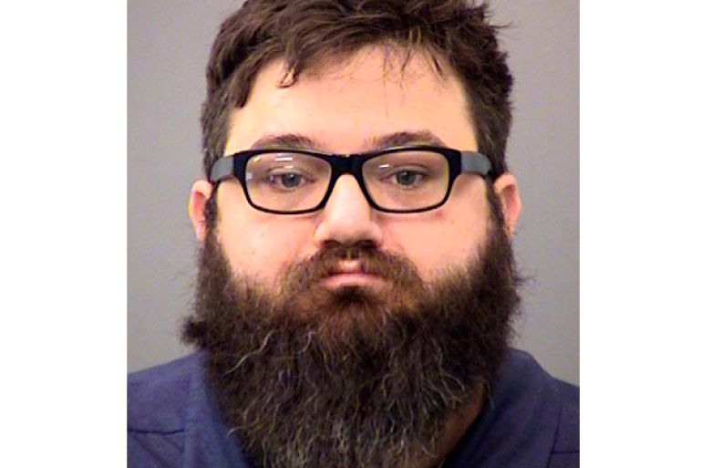 A mugshot of Dustin Passarelli. He has dark hair, a very bushy beard and is wearing glasses.