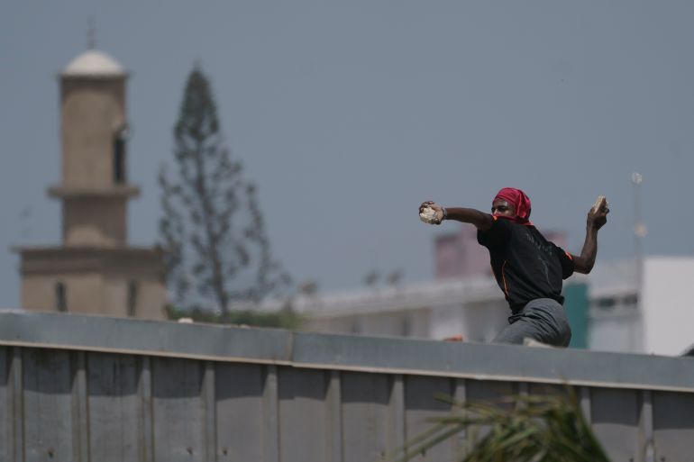 A demonstrator throws a rock at riot policemen during a protest at the Cheikh Anta Diop University campus in Dakar, Senegal,
