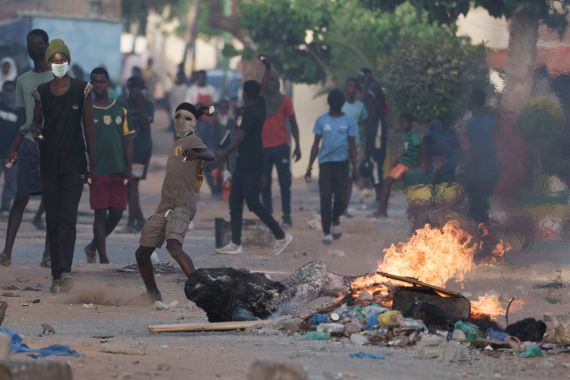 A demonstrator throws a rock at police during a protest at a neighborhood in Dakar