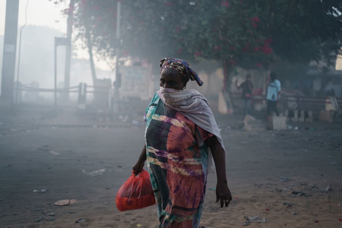 A woman covers her mouth as she walks through the smoke during clashes