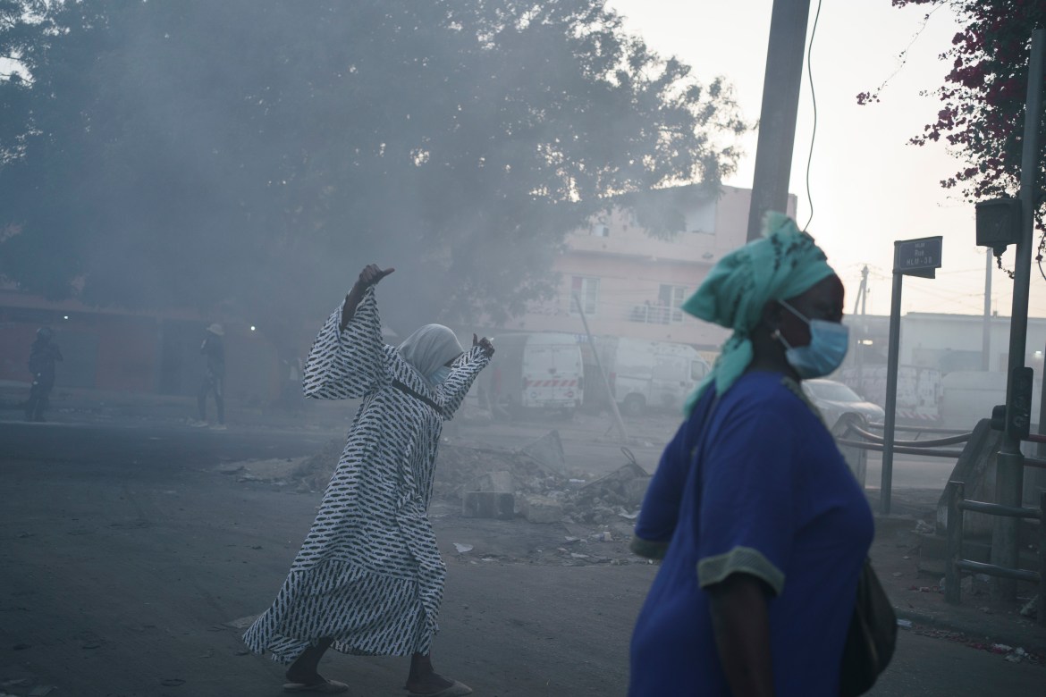 Women cross a street filled with smoke during clashes