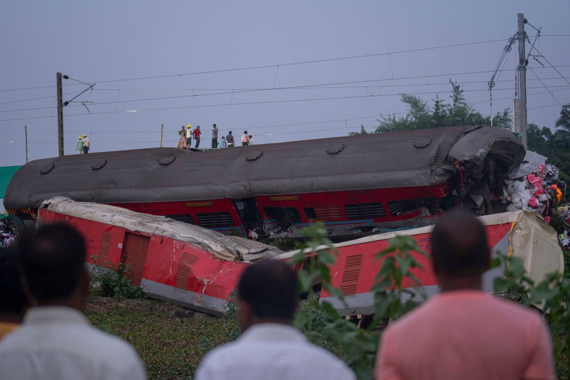 People look at the mangled wreckage of the two passenger trains that derailed Friday
