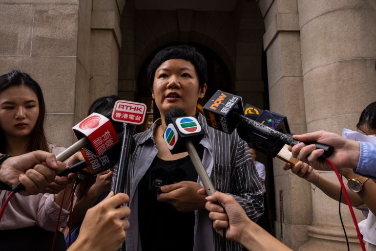 Journalist Bao Choy speaking outside Hong Kong's top court after she was cleared. She is surrounded by microphones held out by local journalists