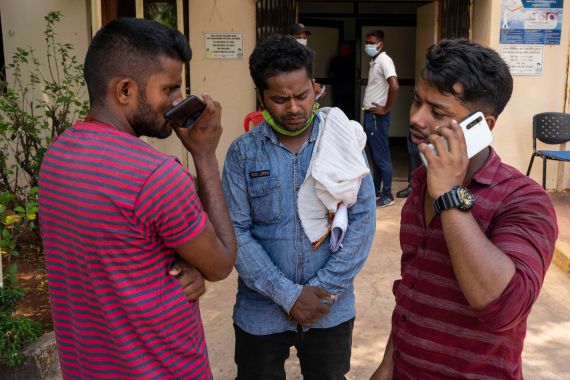 Usman Karim, center, whose brother in law died in Friday's train accident waits with his friends to collect the body