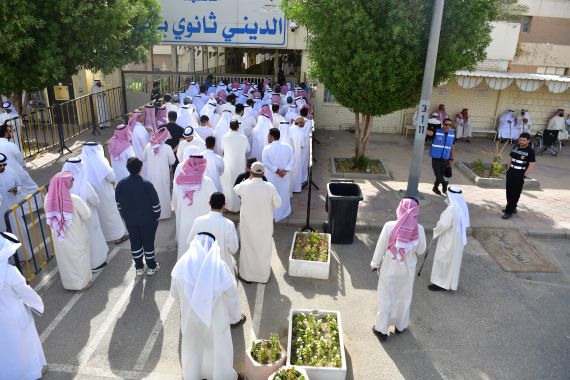 People stand in line to cast their votes in National Assembly elections at a religious school in Sabahiya district, Kuwait, Tuesday, June 6, 2023