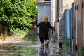 A resident makes her way along a flooded road after the walls of the Nova Kakhovka dam collapsed in Ukraine&#39;s Kherson region [Evgeniy Maloletka/AP Photo]