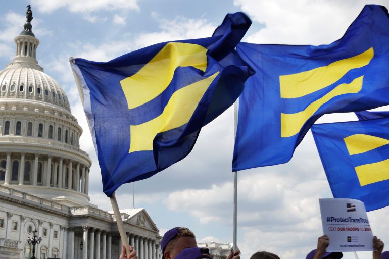 Blue Human Rights Watch flags adorned with yellow equal signs wave in front of Congress.