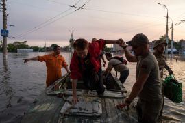 Volunteers evacuate a family from a flooded neighborhood in Kherson [Evgeniy Maloletka/AP Photo]