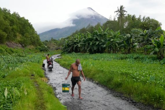 A man walks along a stream near Mayon volcano in Bonga