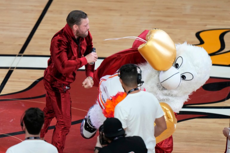 Former MMA fighter Conor McGregor punches Barney, the Miami Heat mascot, during a break in Game 4 of the basketball NBA Finals against the Denver Nuggets, Friday, June 9, 2023, in Miami.  The person in Barney's costume needed medical attention.  (AP Photo/Lynn Sladky)