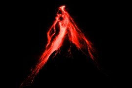 Lava falling from the cone of the Mayon volcano. The lava is a luminous orange against the night sky