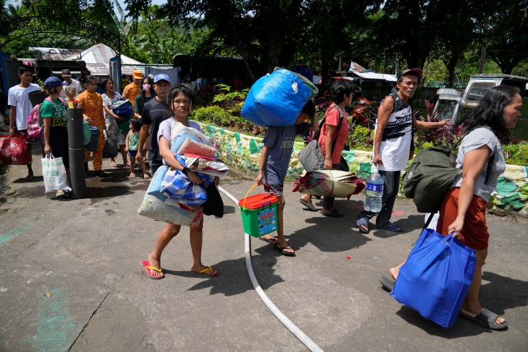 Residents arrive at an evacuation center in Santo Domingo town, Albay province, northeastern Philippines, Tuesday, June 13, 2023. Truckloads of vi