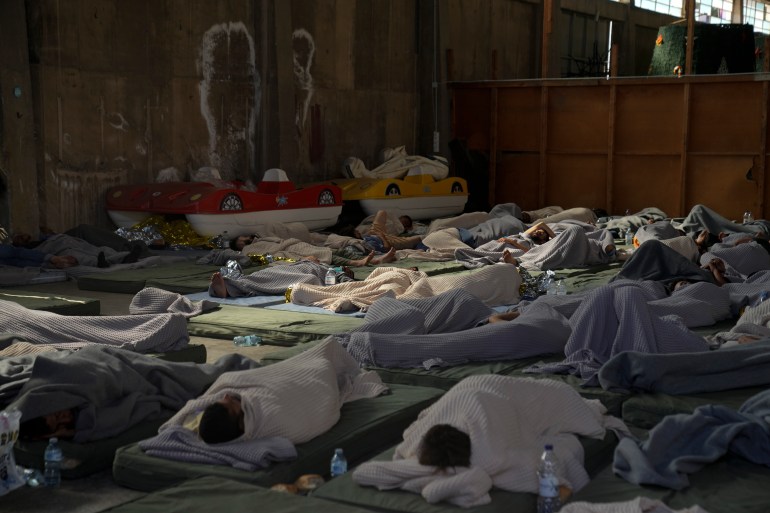 Survivors of a shipwreck sleep in a warehouse at the port in Kalamata