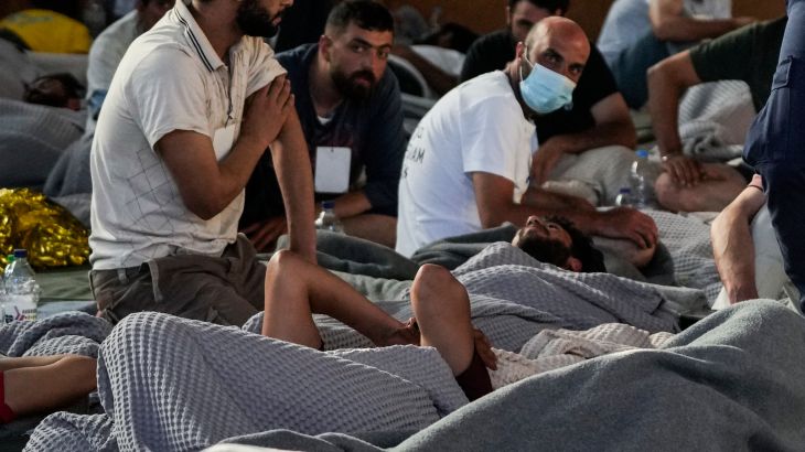 Survivors of a shipwreck rest in a warehouse at the port in Kalamata town