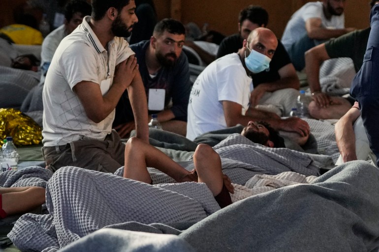 Survivors of the shipwreck rest in a warehouse in the port city of Kalamata
