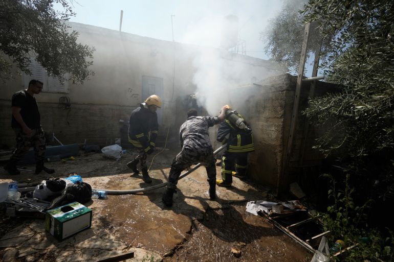 Palestinian firefighters try to extinguish a fire set by Jewish settlers in the West Bank town of Turmus Ayya