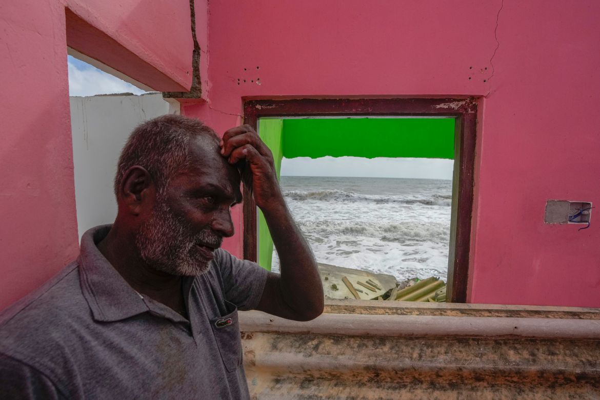 Ranjith Sunimal Fernando gestures as he looks for salvageable items at his home destroyed by erosion in Iranawila