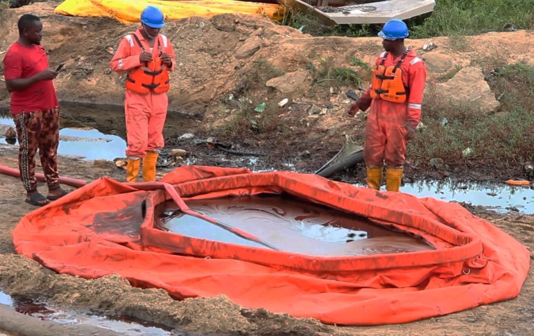 Workers stand next to a container to collect oil spill waste, in Ogoniland, Nigeria, June 16, 2023. [AP Photo]