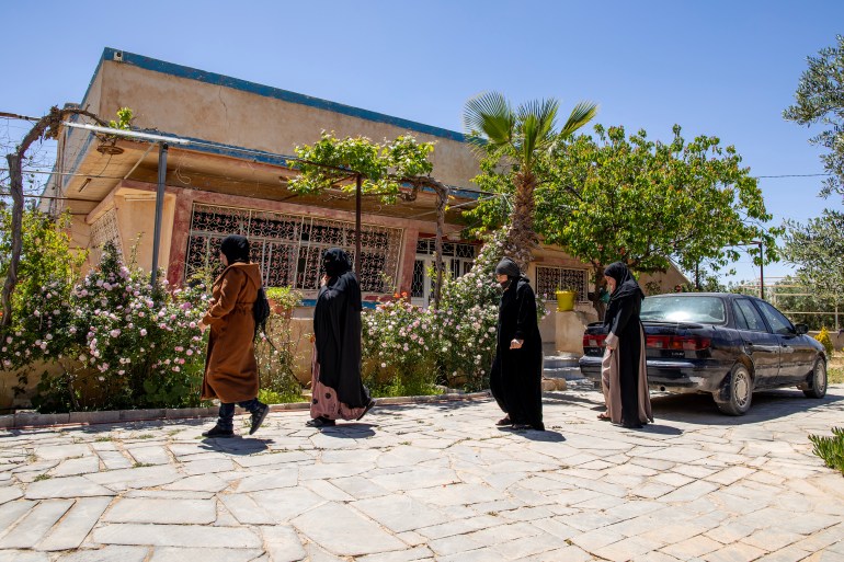 Penduduk lokal desa Umm Al-Quttayn di Al-Mafraq berjalan melewati sebuah rumah di taman bersama tempat mereka menyumbang