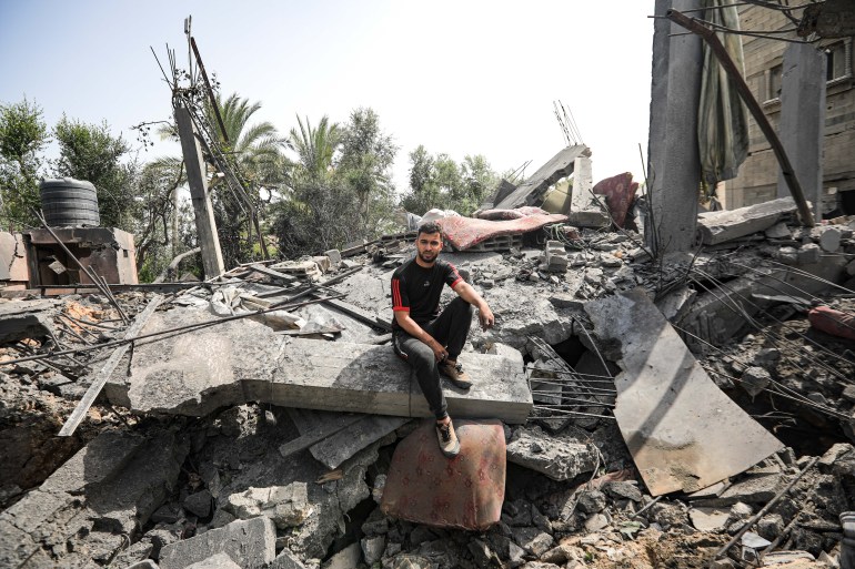A man sits on his home rubble