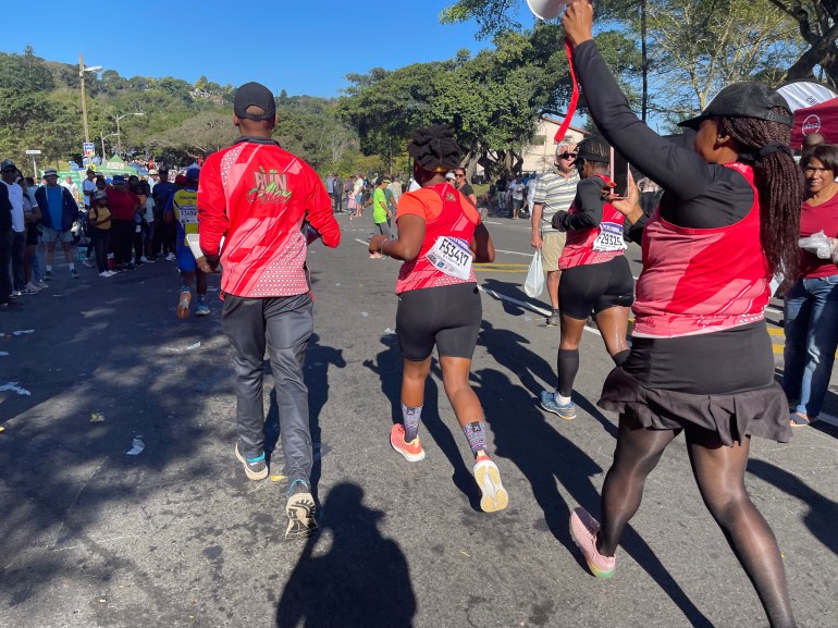 Ashleigh Adams (tengah) menerima sorakan dari rekan satu timnya dari klub lari Run Alex di Pinetown, pinggiran kota Durban, Afrika Selatan, 70 kilometer menuju ultramaraton Kamerad 2023.