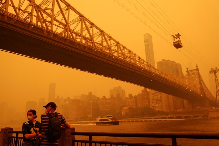Warga memakai topeng di bawah langit oranye saat New York diselimuti asap