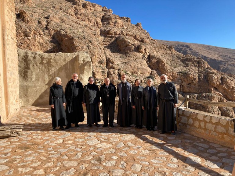 The priests of Mar Musa standing on a sand-coloured terrace