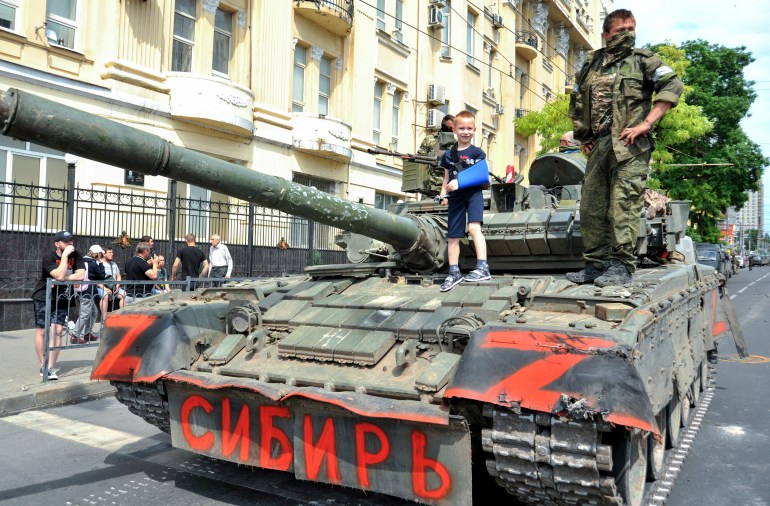 epa10709141 A child poses for a photo on a tank reading 'Siberia' as servicemen from private military company (PMC) Wagner Group block a street in downtown Rostov-on-Don, southern Russia, 24 June 2023. Security and armoured vehicles were deployed after Wagner Group's chief Yevgeny Prigozhin said in a video that his troops had occupied the building of the headquarters of the Southern Military District, demanding a meeting with Russias defense chiefs. EPA-EFE/ARKADY BUDNITSKY