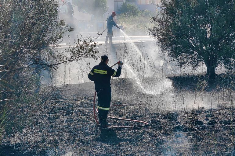 Firefighters work to contain a wildfire in the coastal city of Nafplio, Peloponnese region, Greece
