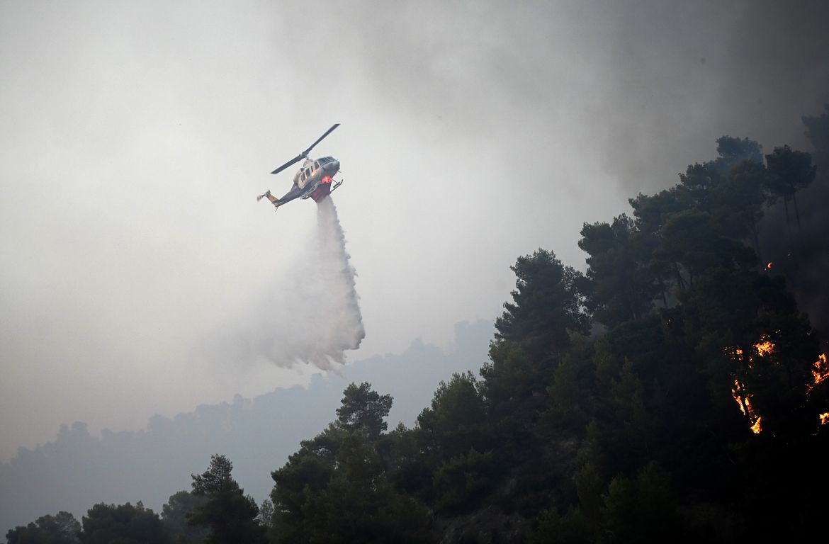 epa10765457 A firefighting helicopter drops water to extinguish a wildfire, in Diakopto, Egio, Greece